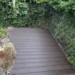 Taras wykonany z deski kompozytowej z zaokrągleniem wokół oczka wodnego