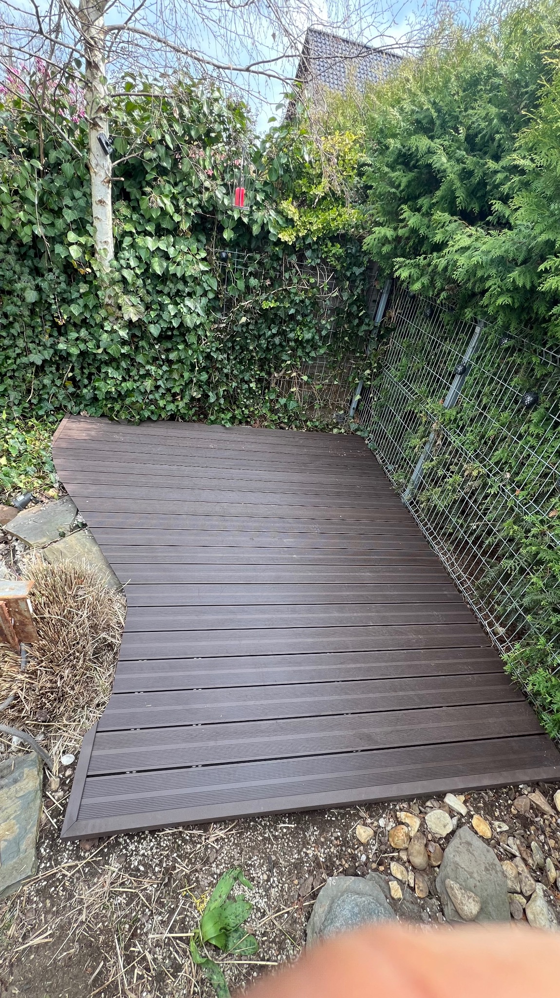 Taras wykonany z deski kompozytowej z zaokrągleniem wokół oczka wodnego