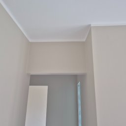 Bogusław Paszek - Jasne ściany po malowaniu z dekoracyjną listwą przysufitową, widoczne fragmenty drzwi i ościeżnicy. Minimalizm i czystość w wykończeniu wnętrza.