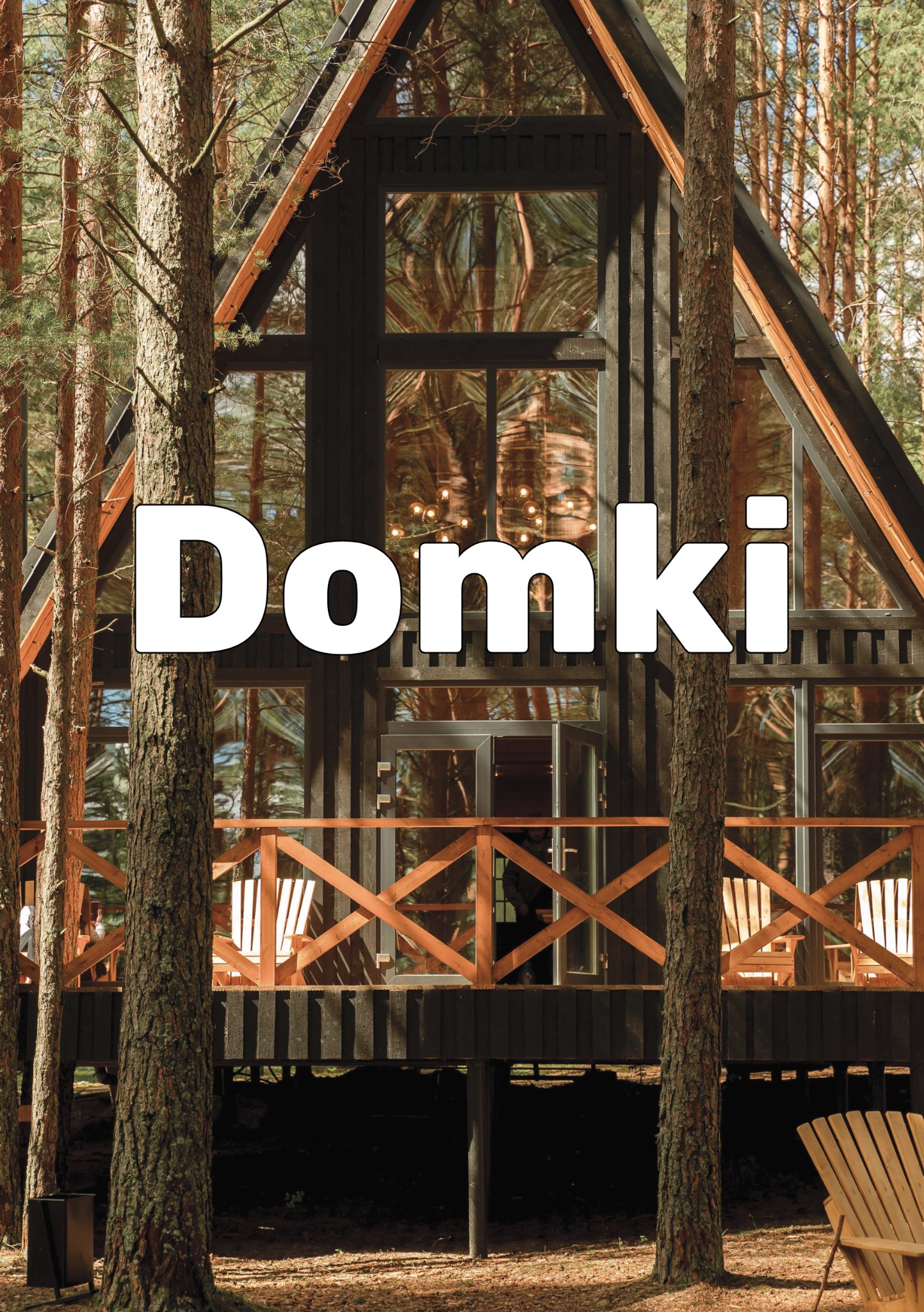 Nowoczesny dom w kształcie litery A z dużymi oknami, drewnianym tarasem i balustradą, wkomponowany w leśny krajobraz z widocznymi pniami drzew.