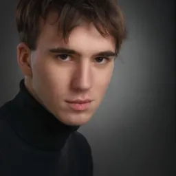 Portret młodego mężczyzny w czarnym golfie, oświetlonego studyjnie na szarym tle, z intensywnym spojrzeniem skierowanym wprost.