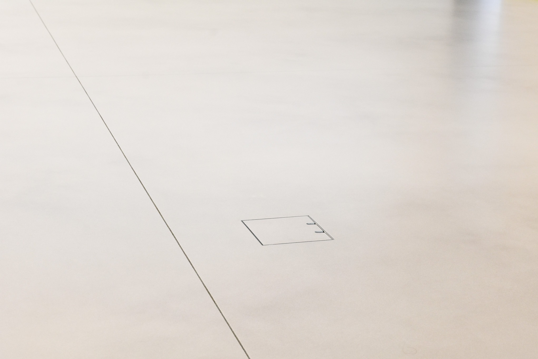 Jasna, jednolita posadzka z delikatną fugą i wbudowaną klapą rewizyjną, widoczna z góry.