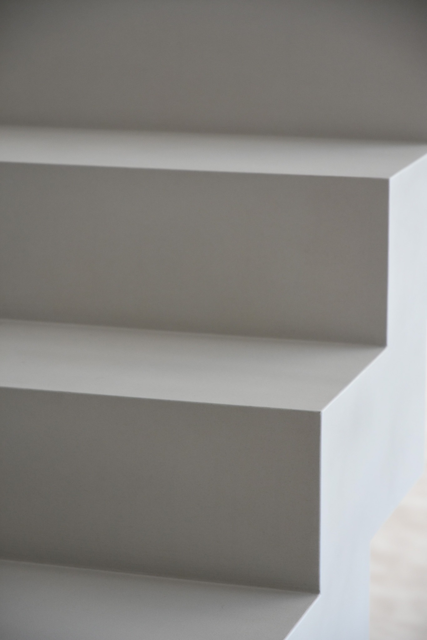 Minimalistyczne schody wewnętrzne w odcieniach szarości, wykończone gładką powierzchnią, z widoczną fakturą na krawędziach stopni.