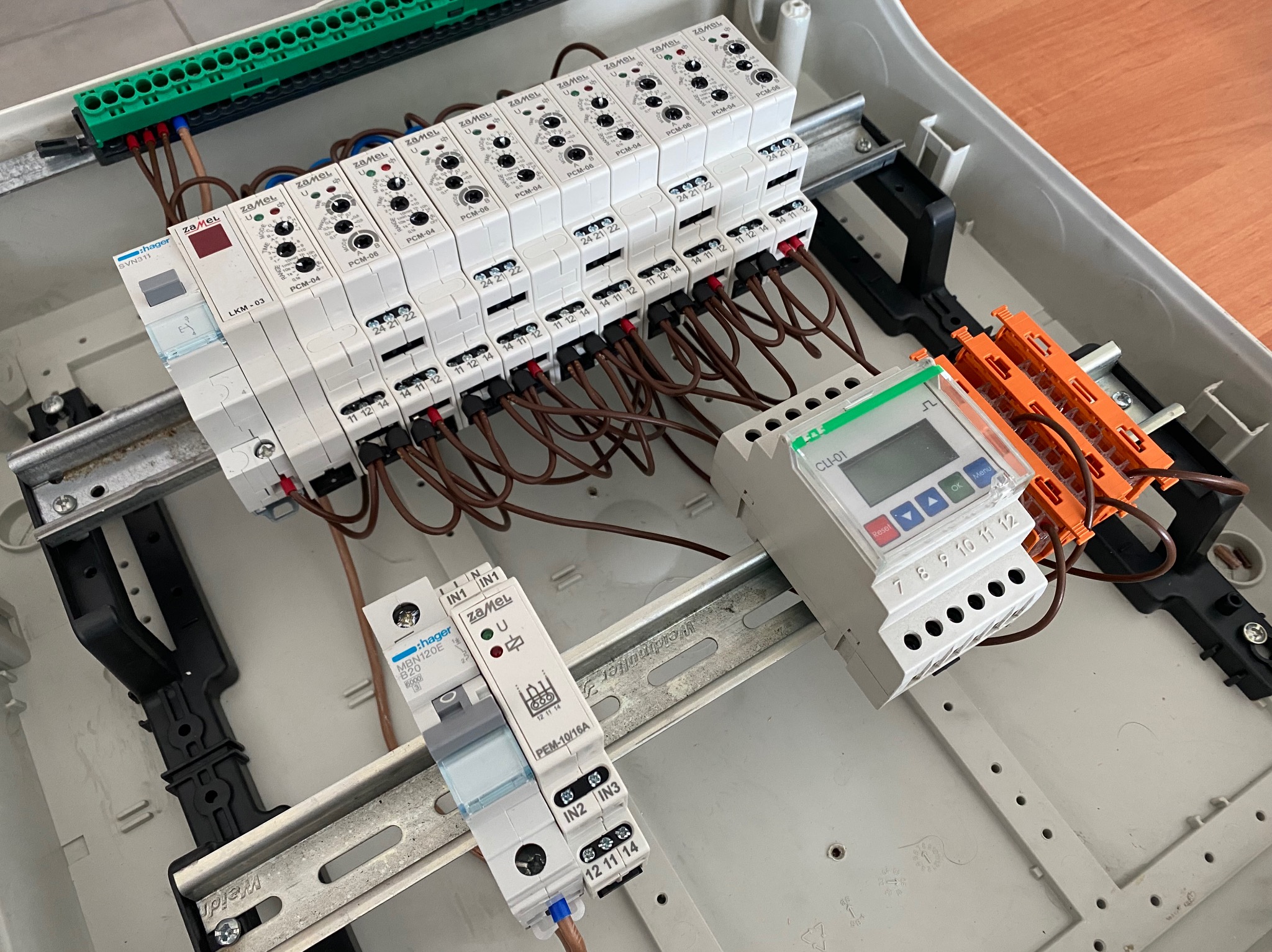 Rozdzielnica elektryczna z zamontowanymi modułami Zamel PCM-04, PCM-06 i Hager, widoczne przewody, szyny montażowe i elementy zabezpieczające. Detal instalacji.