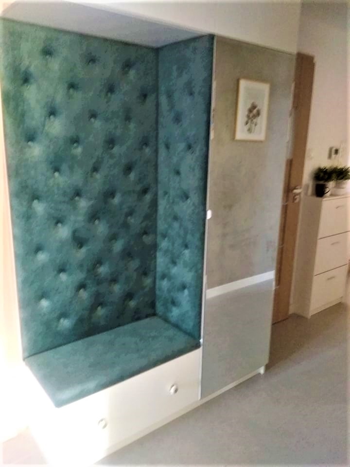 Szafa wnękowa z tapicerowanym siedziskiem i ścianami w odcieniach zieleni, z lustrzanymi drzwiami i widocznym fragmentem wnętrza mieszkania.