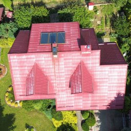 TWINSBRO SPÓŁKA Z OGRANICZONĄ ODPOWIEDZIALNOŚCIĄ - Widok z lotu ptaka na dom z czerwoną dachówką, na której widać ślady czyszczenia, z oknami dachowymi i kominem, otoczony bujnym ogrodem z altaną i drzewami.