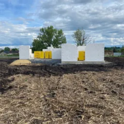 Budowa domu jednorodzinnego w Dzierżysławiu w trakcie wznoszenia ścian z bloczków betonu komórkowego Ytong, z paletami materiałów budowlanych widocznymi wewnątrz powstającego budynku, na tle...