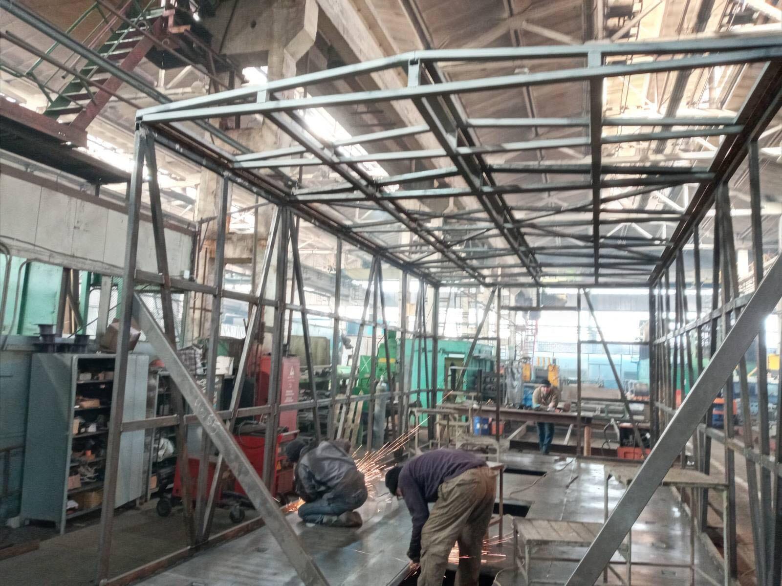 Spawanie konstrukcji metalowej w hali produkcyjnej we Wrocławiu, widoczne iskry, spawacze w kombinezonach oraz szkielet konstrukcji.