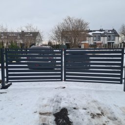 Werka Bramy Weronika Wanczura - Nowoczesna, pozioma brama wjazdowa w kolorze antracytowym, widok z zewnątrz na posesję z zaparkowanym samochodem w zimowej scenerii.