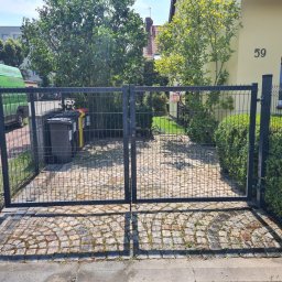 Werka Bramy Weronika Wanczura - Metalowa, dwuskrzydłowa brama wjazdowa z siatki na posesję z brukowanym podjazdem, widok z zewnątrz, na tle zieleni i domu z numerem 59.