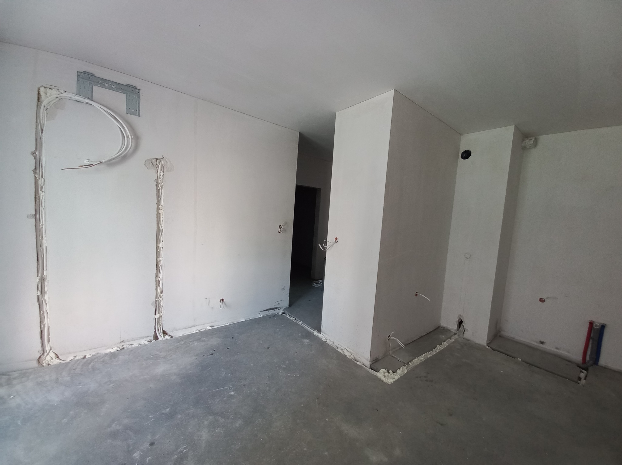 Wnętrze w trakcie prac: widoczne przewody, puszki instalacyjne, pianka montażowa przy podłodze, przygotowania do montażu klimatyzacji na ścianie.