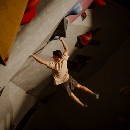 zofia.jpg Zofia Kowalczyk - Młody mężczyzna wspina się na sztucznej ściance, trzymając się różnokolorowych chwytów. Widok z dołu, oświetlenie punktowe podkreśla sylwetkę wspinacza.