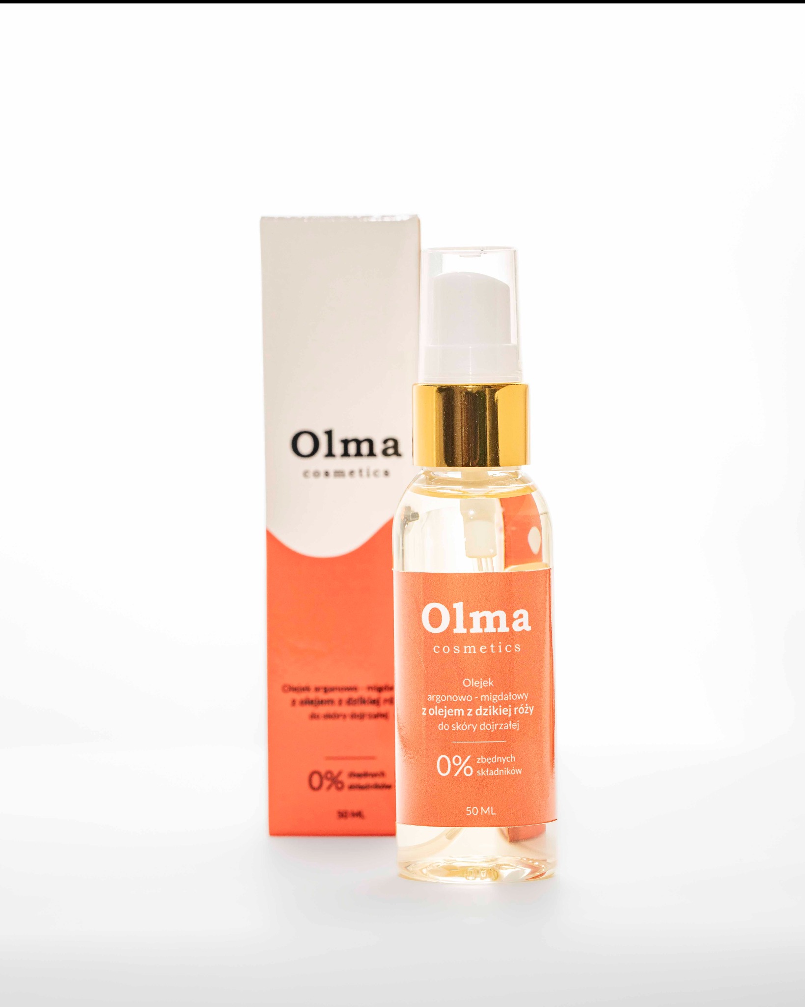 Zdjęcie olejku do twarzy Olma cosmetics w przezroczystej butelce z pompką na białym tle, obok pudełko produktu. Złote wykończenia, minimalistyczny design.