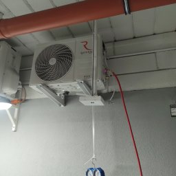 GOWENT SPÓŁKA Z OGRANICZONĄ ODPOWIEDZIALNOŚCIĄ - Biała jednostka wewnętrzna klimatyzacji marki Rotenso zamontowana pod sufitem, pod pomarańczową rurą. Podłączone są do niej przewody pomiarowe manometru w kolorach czerwonym i żółtym.