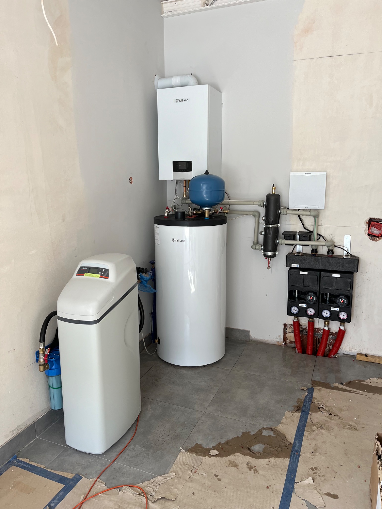 Nowoczesna kotłownia z piecem gazowym Vaillant, zasobnikiem ciepłej wody, stacją uzdatniania wody i rozdzielaczem ogrzewania podłogowego, w trakcie prac wykończeniowych.