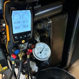 Paweł Hydraulik - Pomiar ciśnienia i temperatury w instalacji chłodniczej za pomocą elektronicznego kolektora Testo 550s i manometru analogowego, widoczne przewody i elementy instalacji.