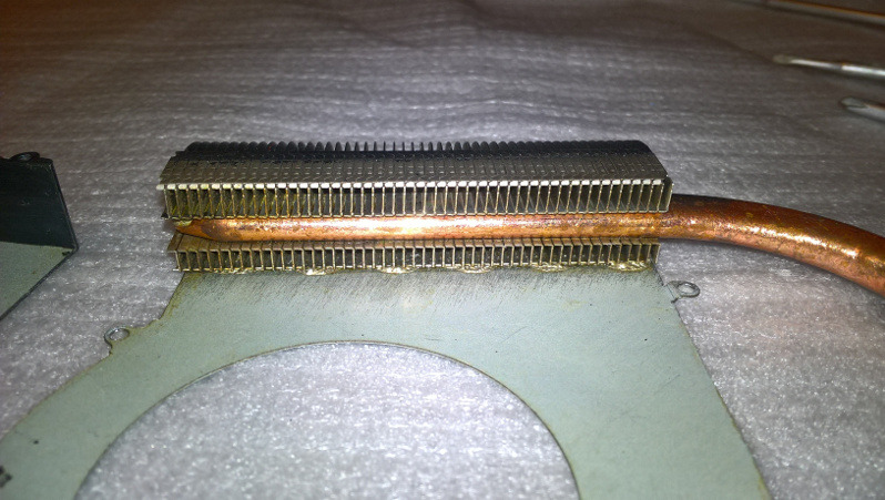 Miedziana rurka cieplna chłodzenia laptopa z aluminiowym radiatorem, widoczne ślady pasty termoprzewodzącej.
