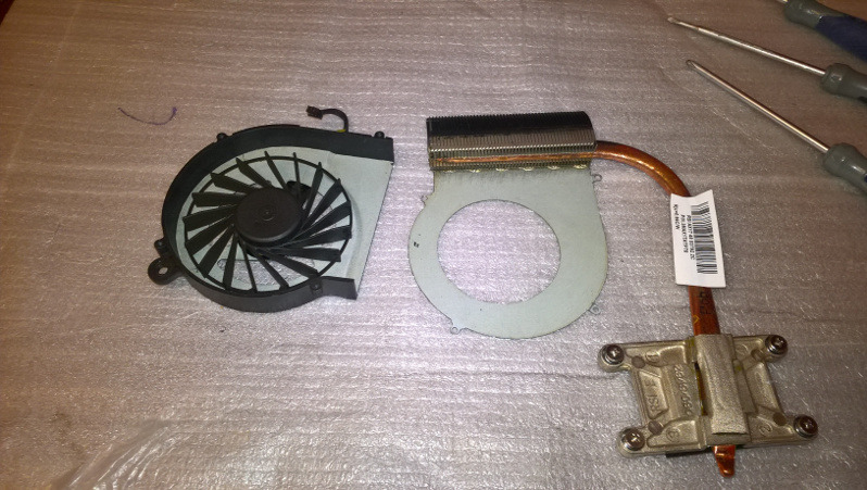 Zdemontowany układ chłodzenia laptopa: wentylator z czarną obudową i radiatorem z miedzianą rurką cieplną, obok leżą śrubokręty na folii bąbelkowej.