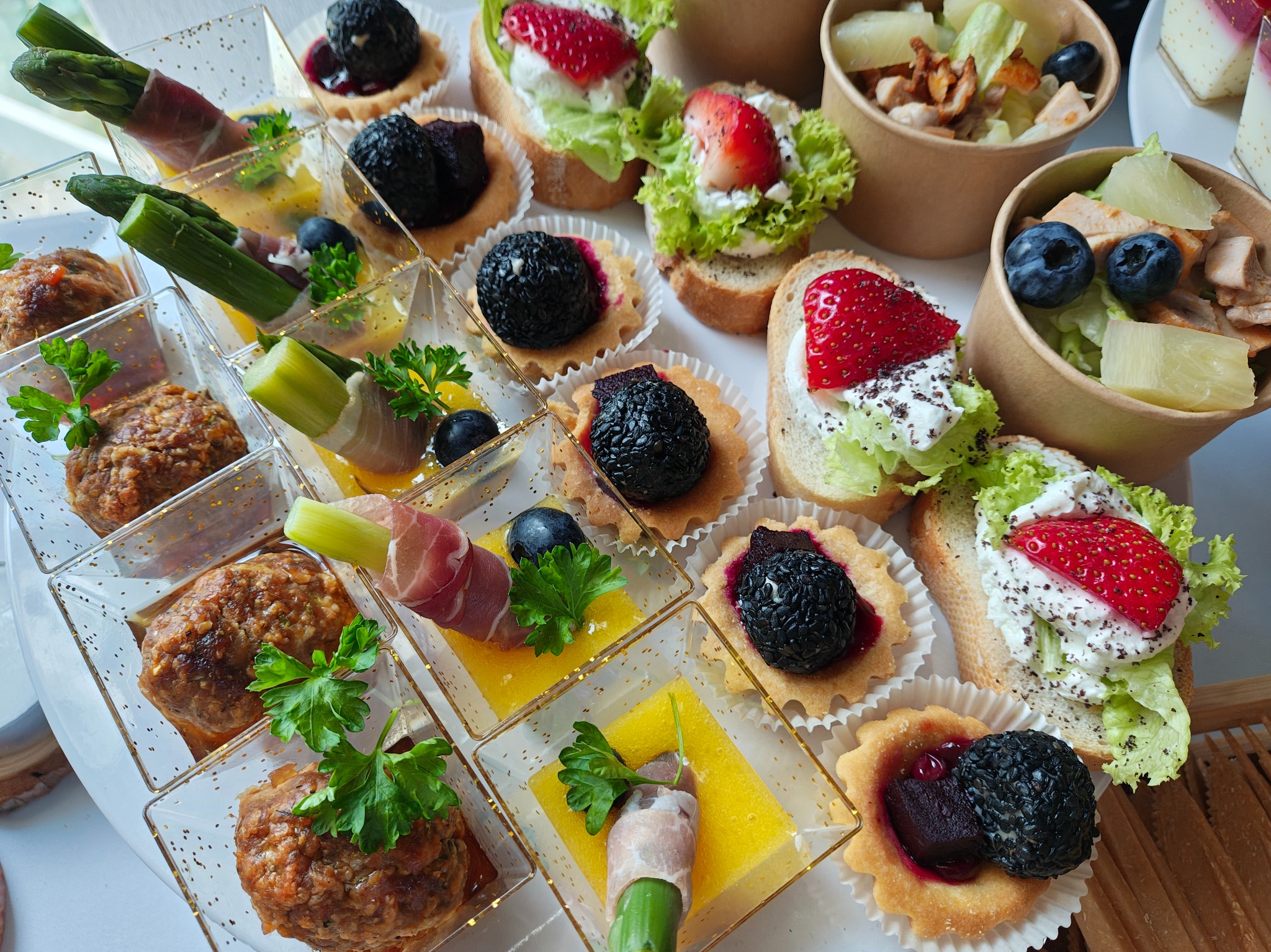 Ekskluzywne przekąski cateringowe: tartaletki z owocami, szaszłyki z szynką parmeńską i warzywami, mini-sałatki w papierowych kubeczkach. Eleganckie i apetyczne.