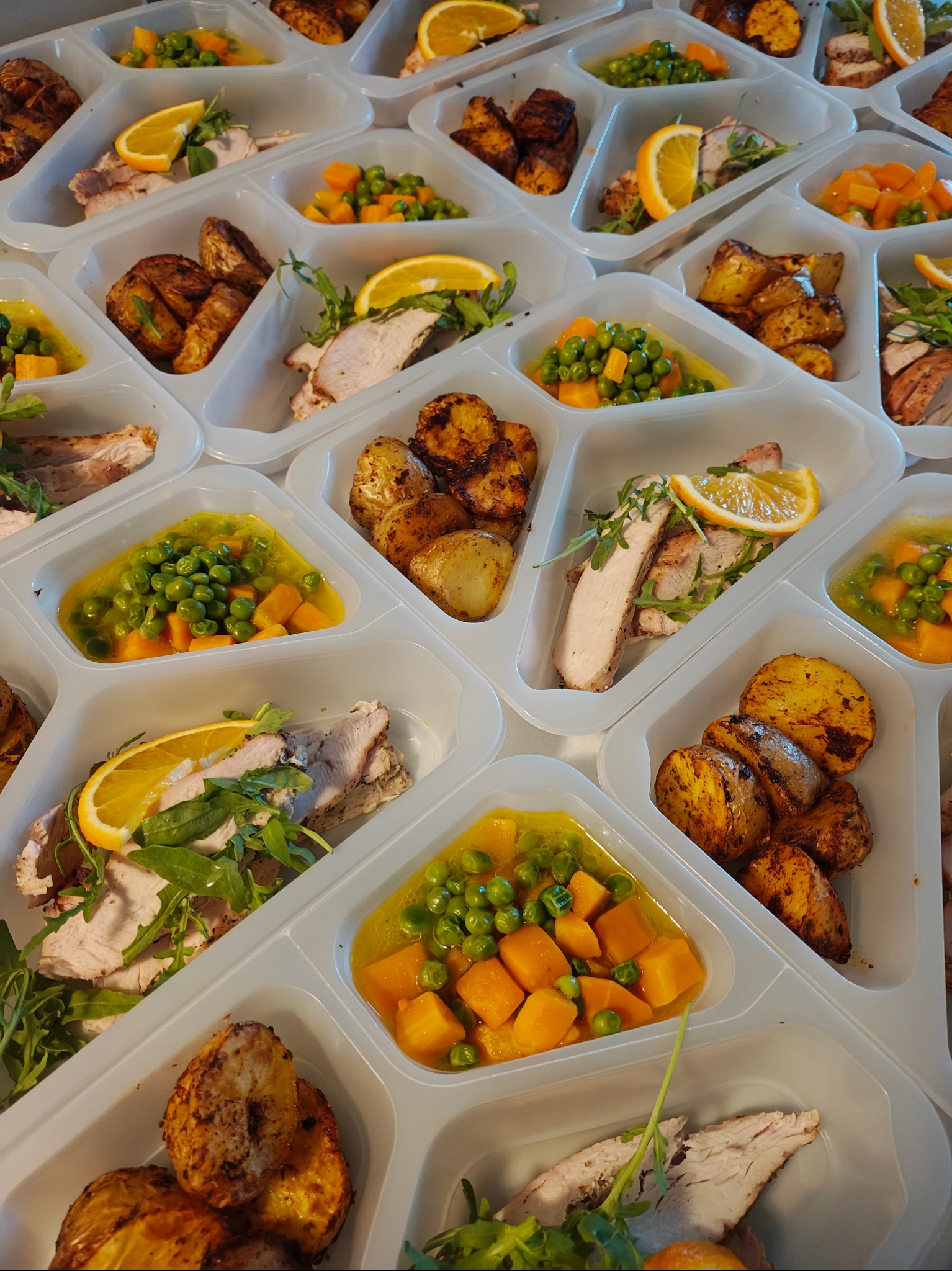 Gotowe zestawy obiadowe w plastikowych pojemnikach z pieczonym mięsem, ziemniakami i warzywami, przygotowane przez firmę cateringową z Kobyłki.