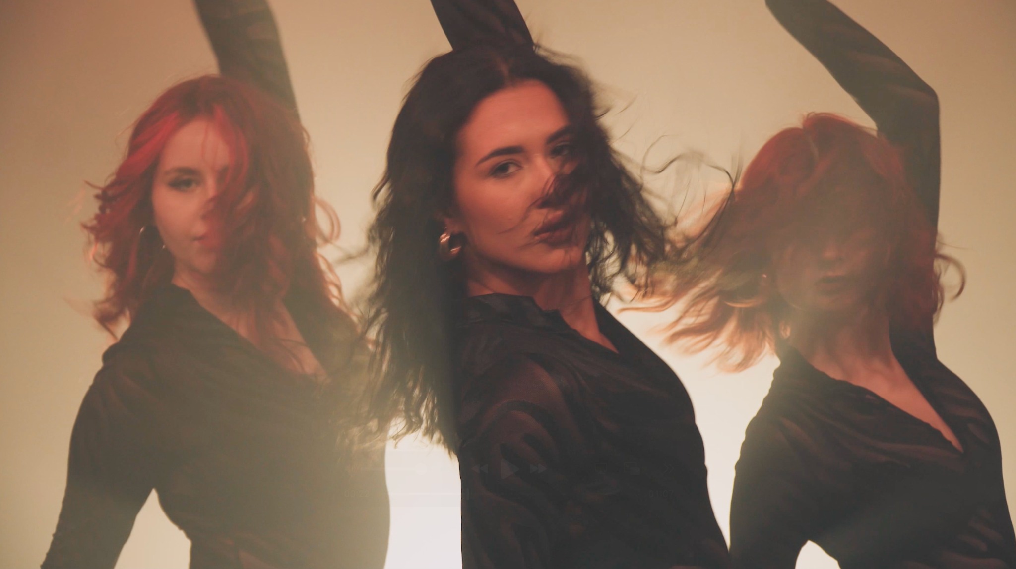 Kobieta z rozwianymi włosami w czarnej sukience, w potrójnym ujęciu na rozmytym, ciepłym tle.