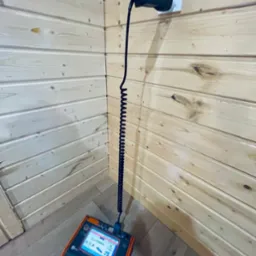 Miernik elektryczny podłączony do gniazdka w drewnianej ścianie, wyświetlający wynik pomiaru impedancji pętli zwarcia ZL=0.860 Ω.