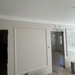 Finezja Wykończeń Krzysztof Chrobak - Eleganckie wykończenie ścian z dekoracyjnymi listwami i gładką powierzchnią. Parkiet w jodełkę. Fragment instalacji elektrycznej i przygotowania do montażu drzwi.