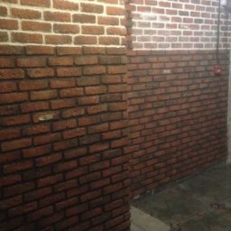 AKT GRUP Yevhen Sobko - Ściana wyłożona cegłą w dwóch odcieniach, z fragmentem pomalowanym na biało, widoczna w Krakowie, z niedokończoną podłogą.