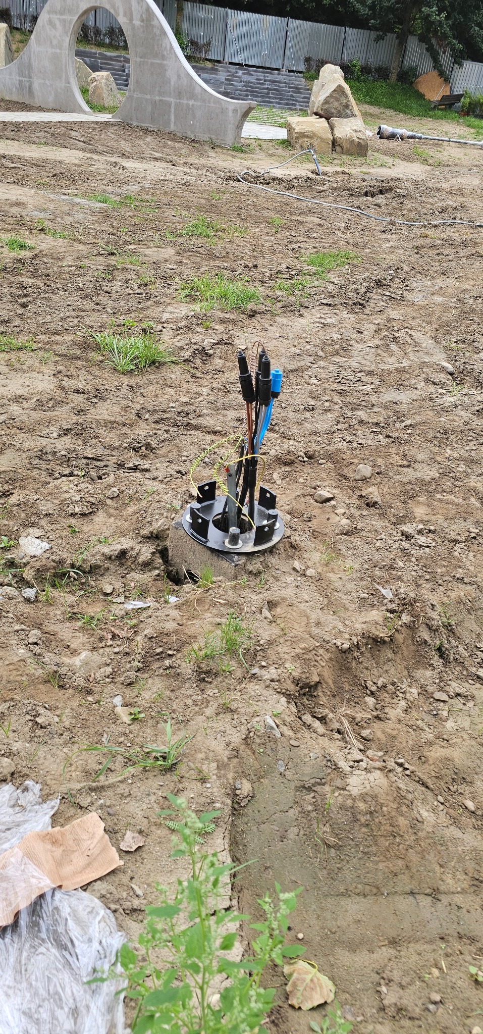 Uziemienie instalacji odgromowej w gruncie z widocznymi przewodami i elementami montażowymi na tle ziemi i elementów architektury krajobrazu.