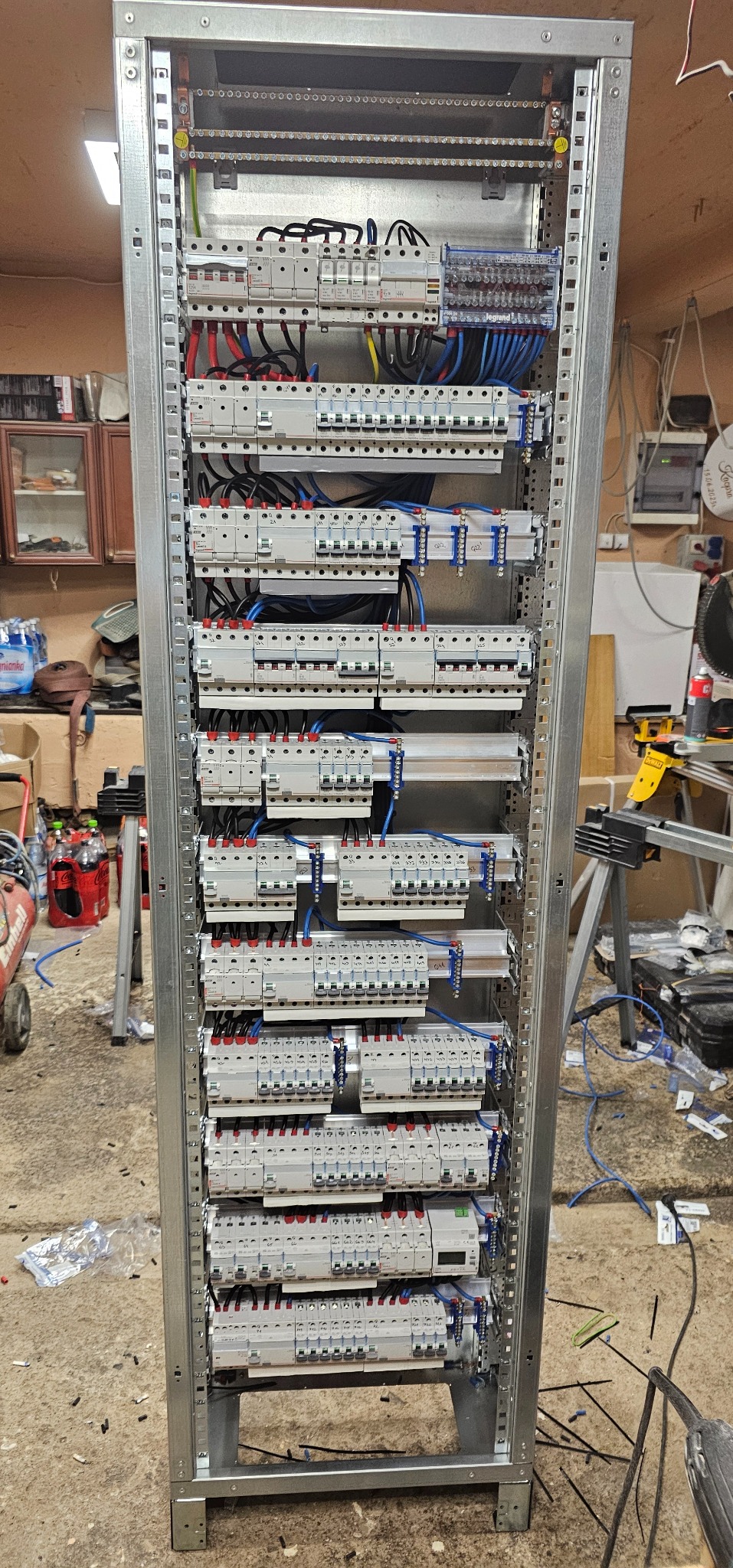 Rozdzielnica elektryczna w metalowej obudowie, widok z przodu. Liczne zabezpieczenia i okablowanie. Instalacja wykonana w schludny sposób.