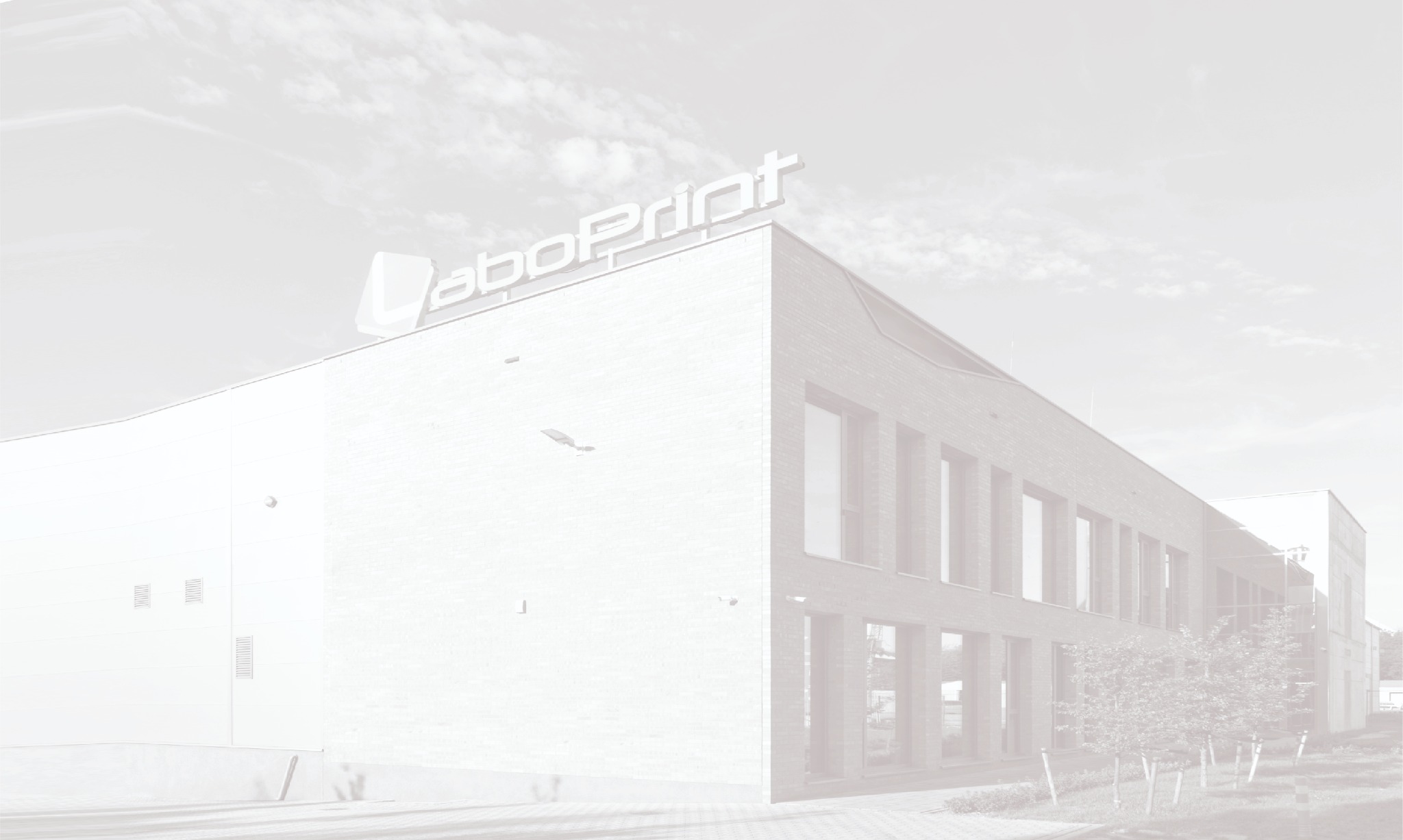 Budynek drukarni z dużym logo na dachu, widok z dołu w pochmurny dzień.