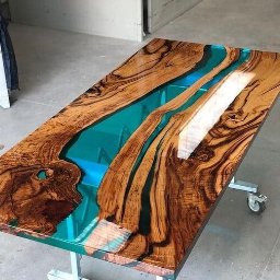 Efekt Skowrońscy s.c. - Stół z drewna egzotycznego z żywicą epoksydową w kolorze turkusowym, na metalowej podstawie z kółkami.