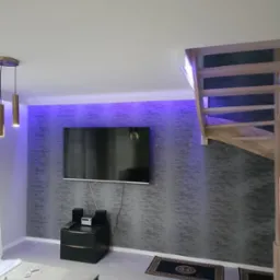 Nowoczesny salon z podświetloną ścianą, telewizorem, schodami drewnianymi i ciemnymi dywanikami z greckim wzorem.