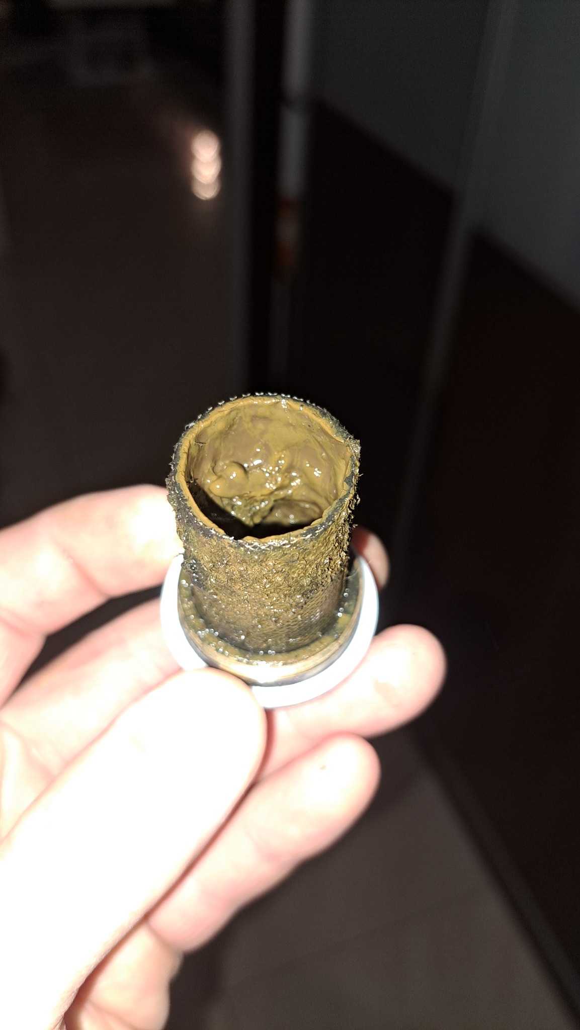 Zatkany element instalacji wodnej, trzymany w dłoni. Wnętrze rury wypełnione osadem i zanieczyszczeniami. Widoczne ślady korozji i zużycia. Bliskie ujęcie.