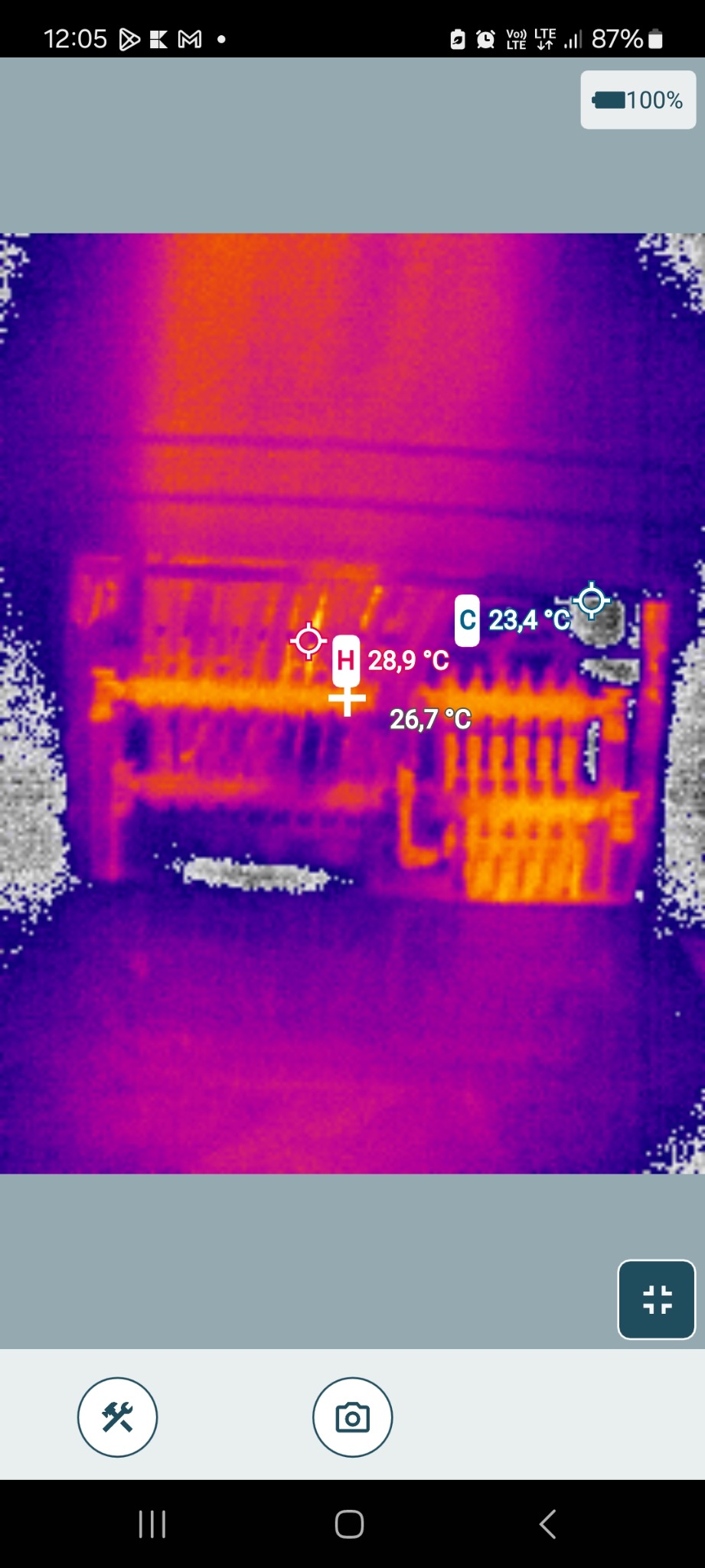 Termowizyjne zdjęcie rozdzielnicy elektrycznej, ukazujące temperaturę poszczególnych elementów. Widoczne oznaczenia temperatur w stopniach Celsjusza.