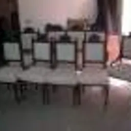 Rząd sześciu krzeseł z jasną tapicerką i ciemnymi drewnianymi ramami, ustawionych w pomieszczeniu z jasnymi ścianami i podłogą, widoczny fragment okna po prawej stronie.