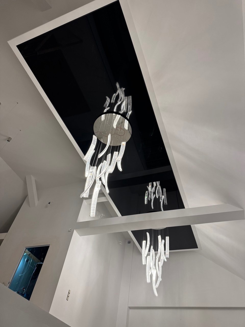 Nowoczesne wnętrze z czarnym sufitem podwieszanym i dekoracyjnym oświetleniem. Widok z dołu, podkreślający geometrię i design.