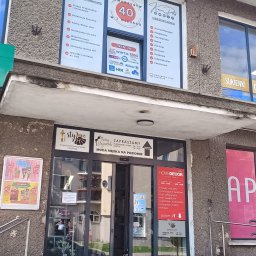 KRAINA PODATKÓW - BIURO RACHUNKOWE KAROLINA BUŚ - Fasada budynku z szyldami firm: biuro rachunkowe 'Kraina Podatków', ubezpieczenia, sklepy odzieżowe 'Stylove' i 'Modny Elegancik' oraz 'Home Decor'.
