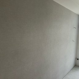 GLAZUROWSKY - Gładka, szara ściana z fakturą w nowym wnętrzu, z widocznymi przewodami i instalacją. Minimalistyczny design, świeżo po malowaniu.