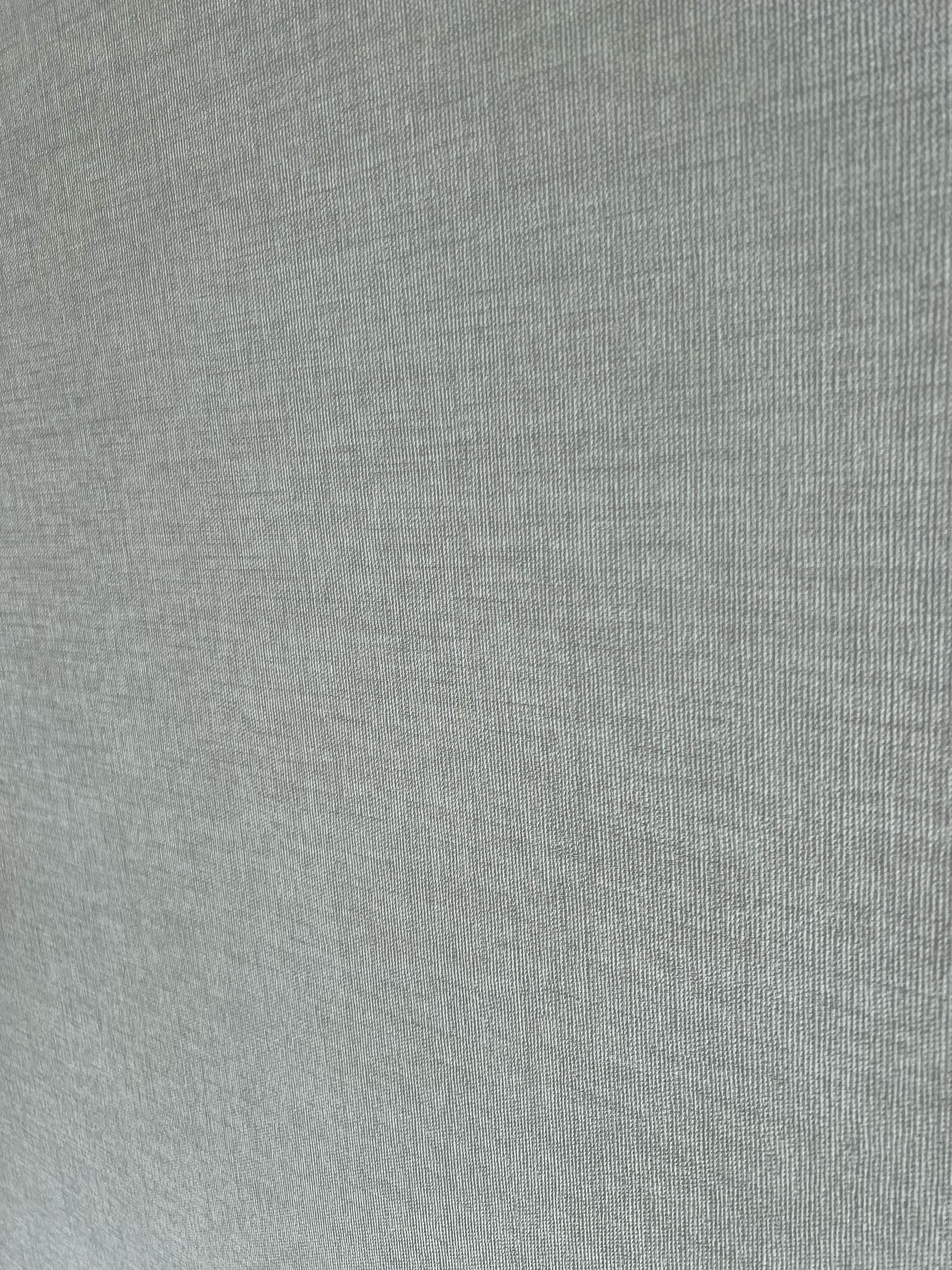Szara tapeta z delikatną teksturą pionowych prążków, widoczna z bliska. Wykończenie wnętrza w Bydgoszczy.