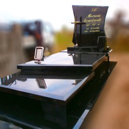 Kamieniarstwo GRANBUD Waldemar Rycyk - Czarny, polerowany pomnik z wygrawerowanym złotym napisem 'Mariusz Eisenbardt' i datami urodzenia i śmierci, zwieńczony złotym krzyżem; mała ramka na zdjęcia po lewej stronie.
