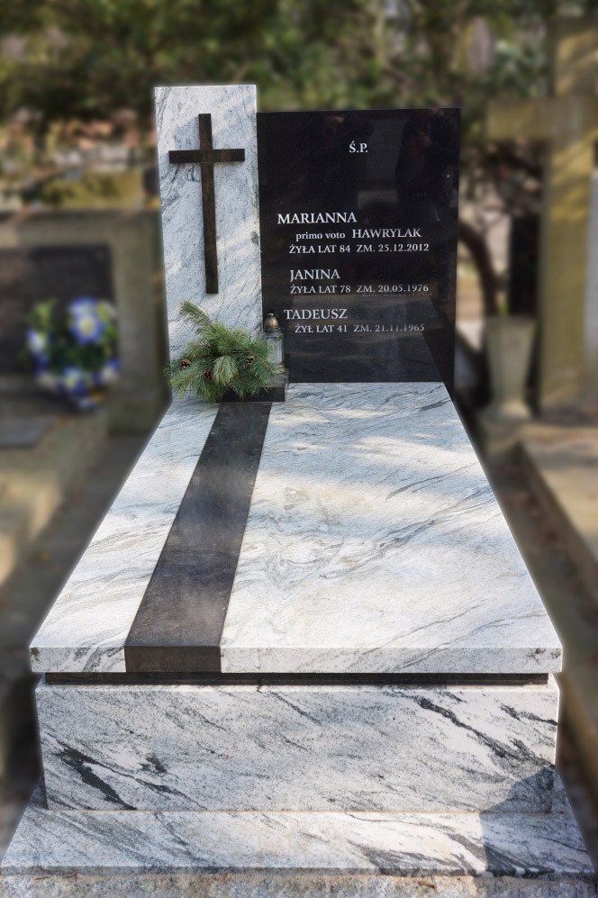 Granitowy pomnik z czarną tablicą nagrobną i białym krzyżem, udekorowany gałązką świerku i zniczem, na tle cmentarza.
