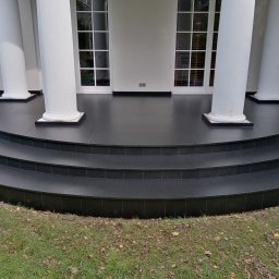 Volodymyr KUZ - Elegancki taras z czarnych płytek kamiennych z trzema stopniami, otoczony białymi kolumnami i zielonym trawnikiem z opadłymi liśćmi.