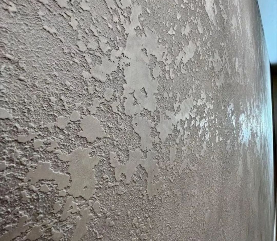 Szara ściana z dekoracyjną strukturą gładzi, efekt nierównomiernego nałożenia, widoczna faktura.