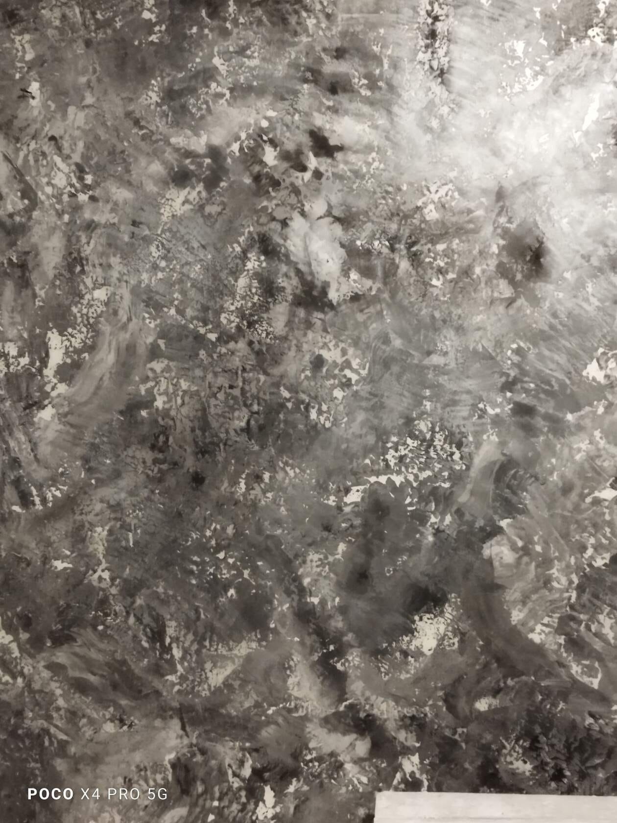 Szara ściana z efektem dekoracyjnym, imitującym beton, z widocznymi śladami pędzla i nieregularną fakturą.