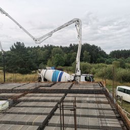 Krzyś Bud Usługi Ogólnobudowlane Krzysztof Dura - Betoniarka z pompą podaje beton na strop Teriva, widoczne zbrojenie i pustaki szalunkowe, w tle las i pochmurne niebo.
