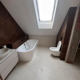 Yurii Tukalo Yurii_bud - Nowoczesna aranżacja łazienki na poddaszu w Sosnowcu. Uwagę przykuwa okno dachowe, wolnostojąca wanna i umywalka nablatowa. Ciekawa okładzina ścienna imitująca drewno.