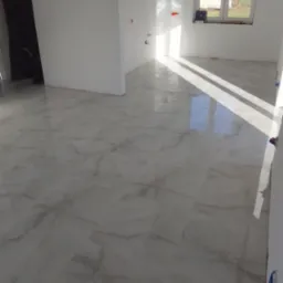 Jasne, marmurowe płytki podłogowe z widocznymi smugami światła słonecznego w nowym, pustym pokoju z białymi ścianami i oknem.