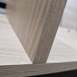 Linea Premium - Fragment drewnianej półki z widoczną strukturą drewna i krawędzią, zbliżenie na łączenie elementów.