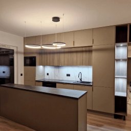 Linea Premium - Nowoczesna kuchnia z wyspą, fronty szafek w odcieniach beżu i drewna, marmurowy backsplash, oświetlenie LED w kształcie pierścieni